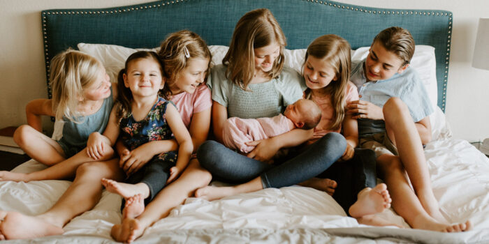 7 siblings on a bed newborn photo session pose idea