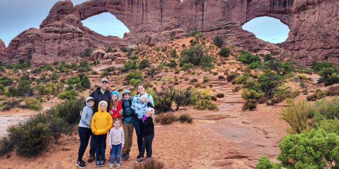Family standing in front of the Window Arches at Arches National Park.
